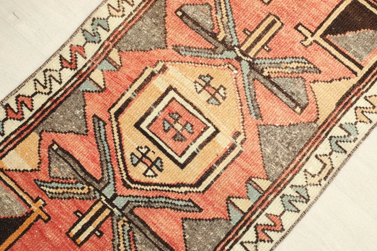 Close-up angle view of the rust, beige, and gray geometric patterns on the vintage wool rug.
