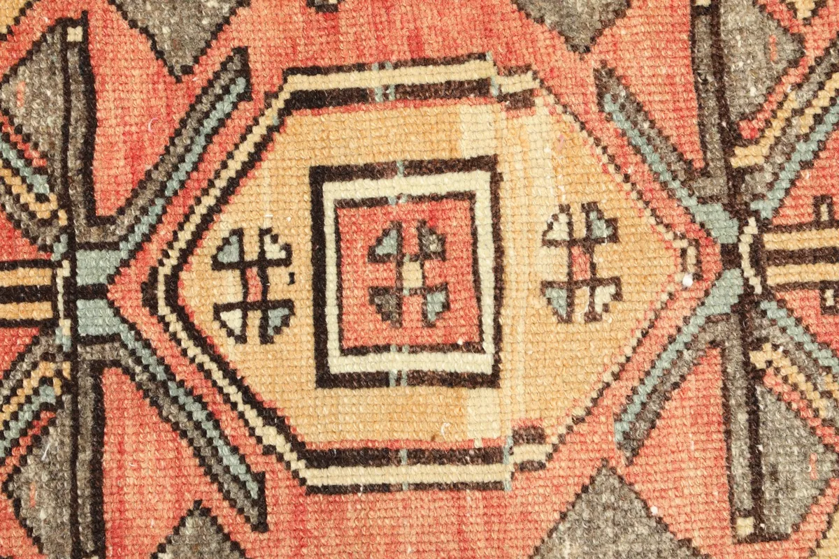 Detailed view of the central medallion and tribal motifs with rust, beige, and black colors.