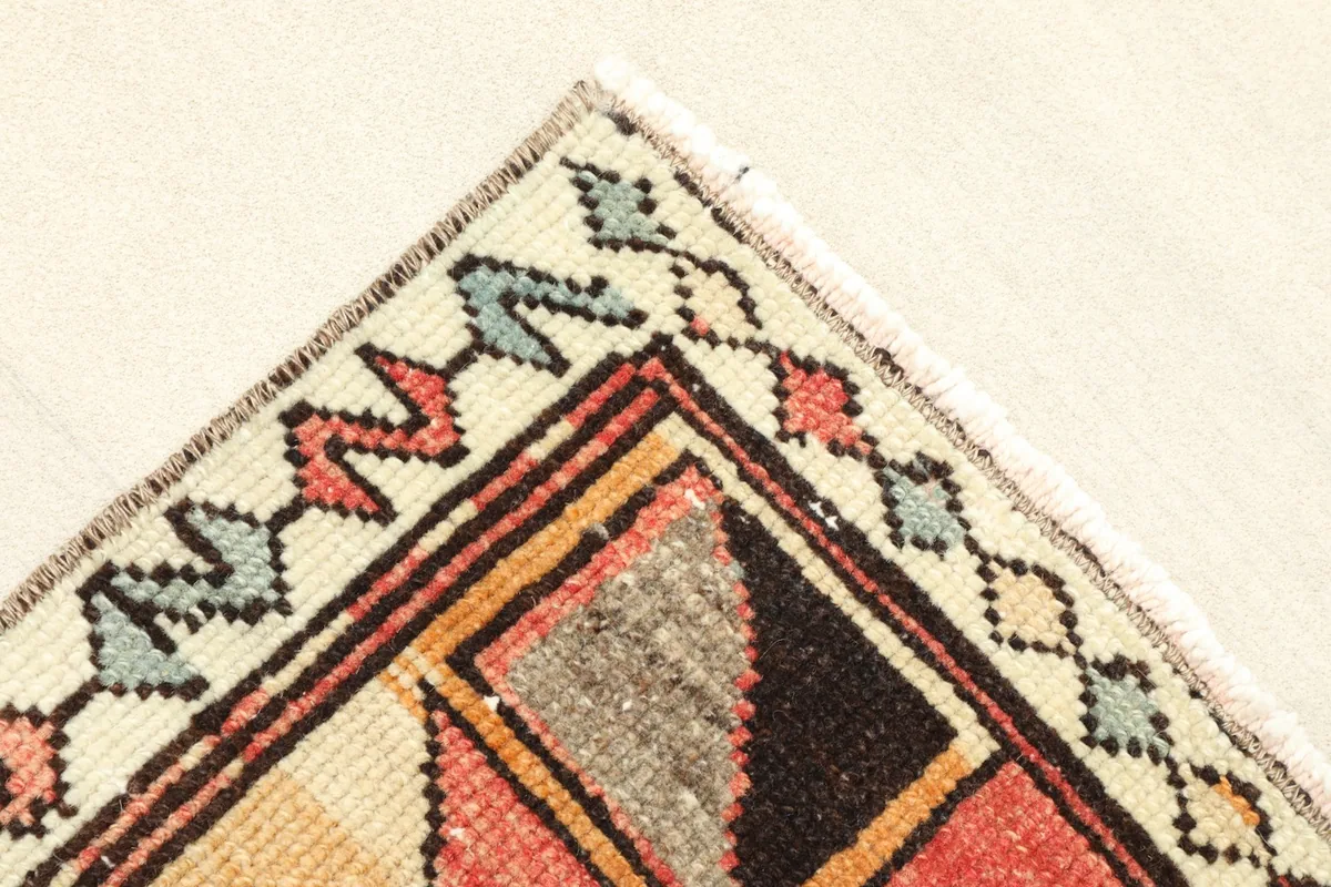 Corner detail showing the intricate beige border design and the hand-knotted fringe.