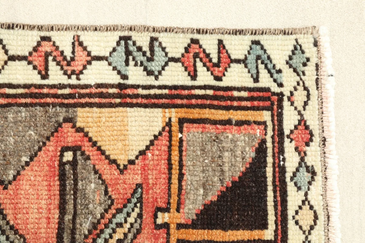 Close-up of the side border featuring zigzag patterns in beige, rust, and blue tones.