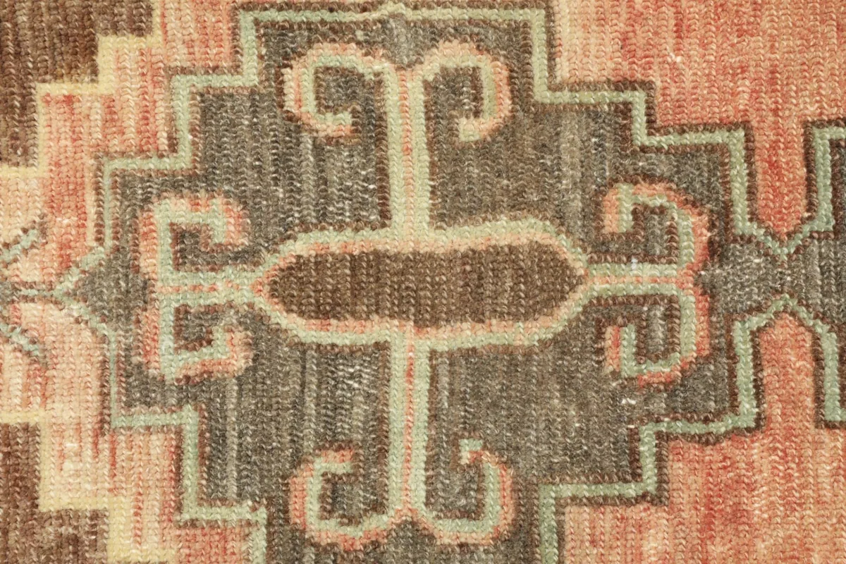 Close-up detail of the central geometric motif in rust, brown, and beige tones