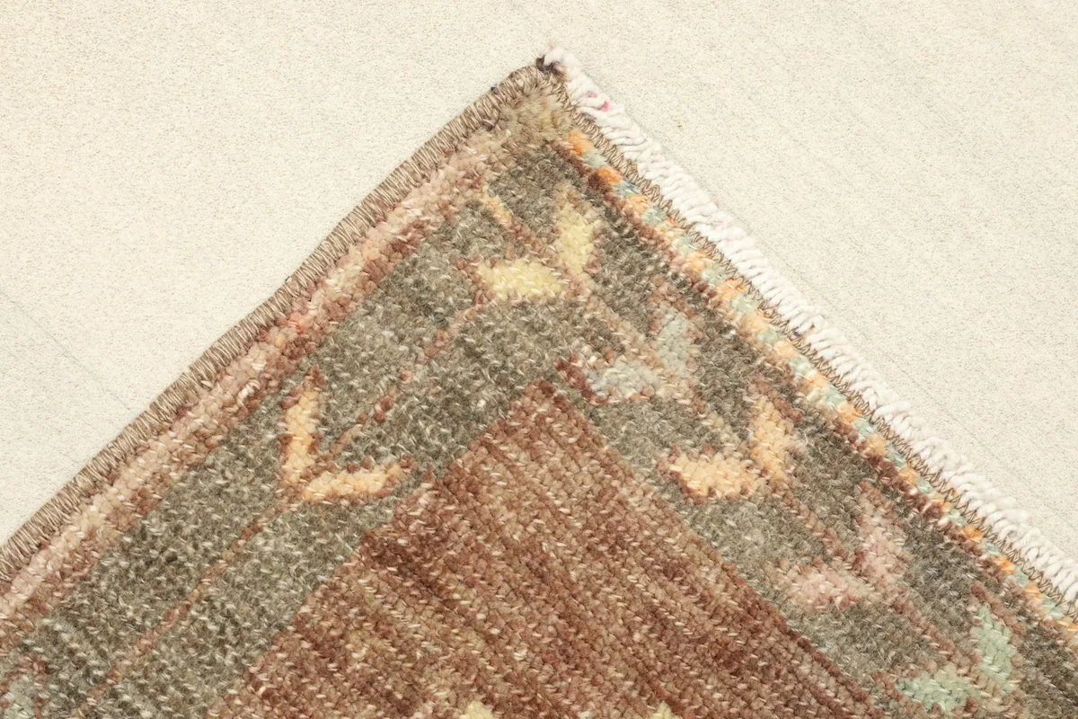 Corner detail showing the edge and fringe of the brown vintage wool rug