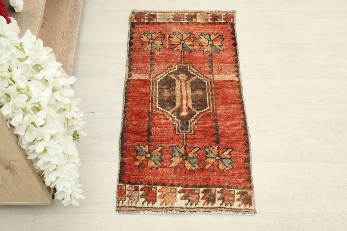 Direct overhead shot showcasing the red field and geometric motifs of the rug