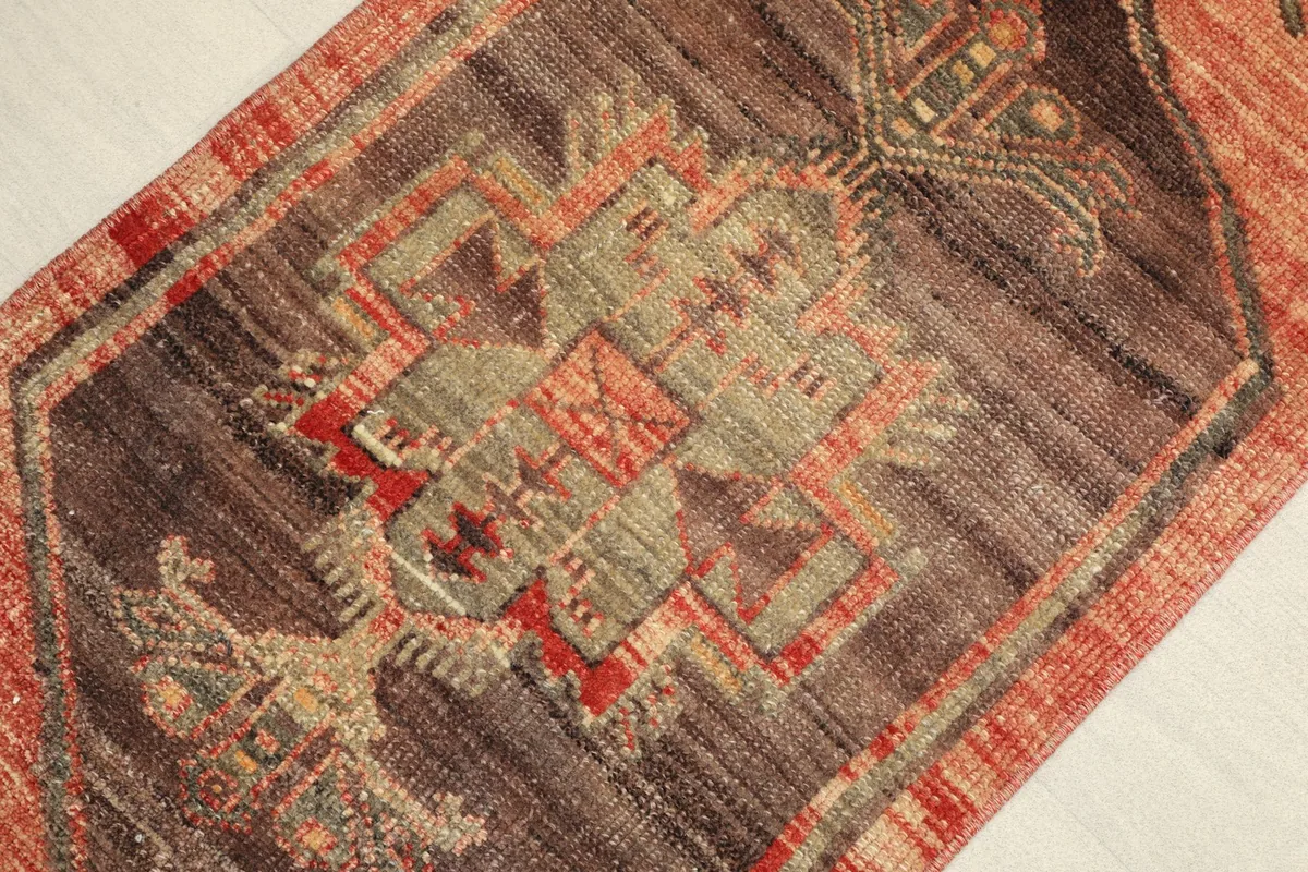 Close-up of the central tribal medallion with geometric patterns in brown, olive, and red tones.