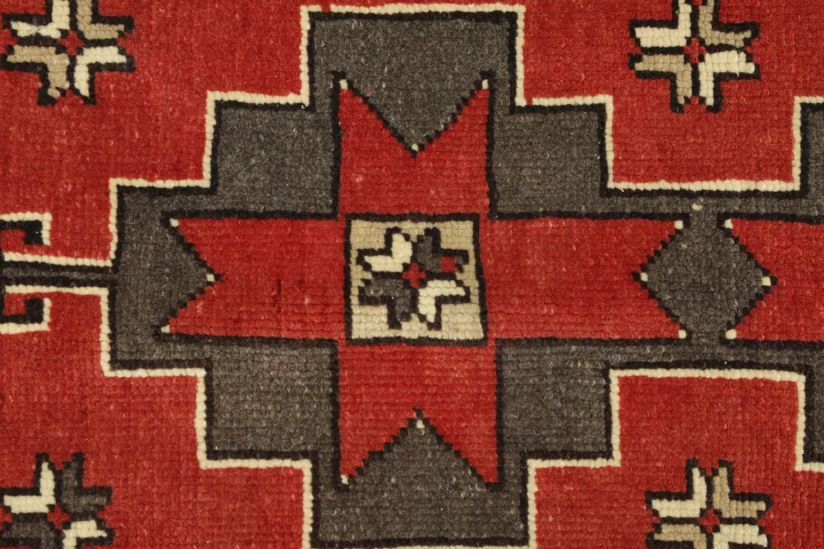Close-up detail of the hand-knotted red and charcoal geometric motif.