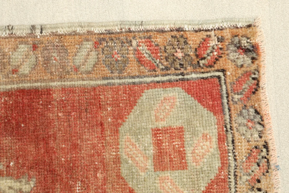 Detail of the rug's border, revealing the faded colors and low pile from age.
