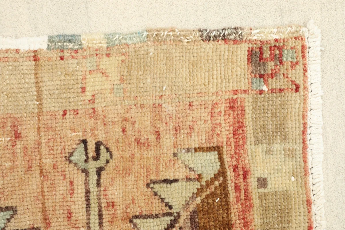 Close-up of the low pile texture and the aged appearance of the wool fibers at the rug edge.