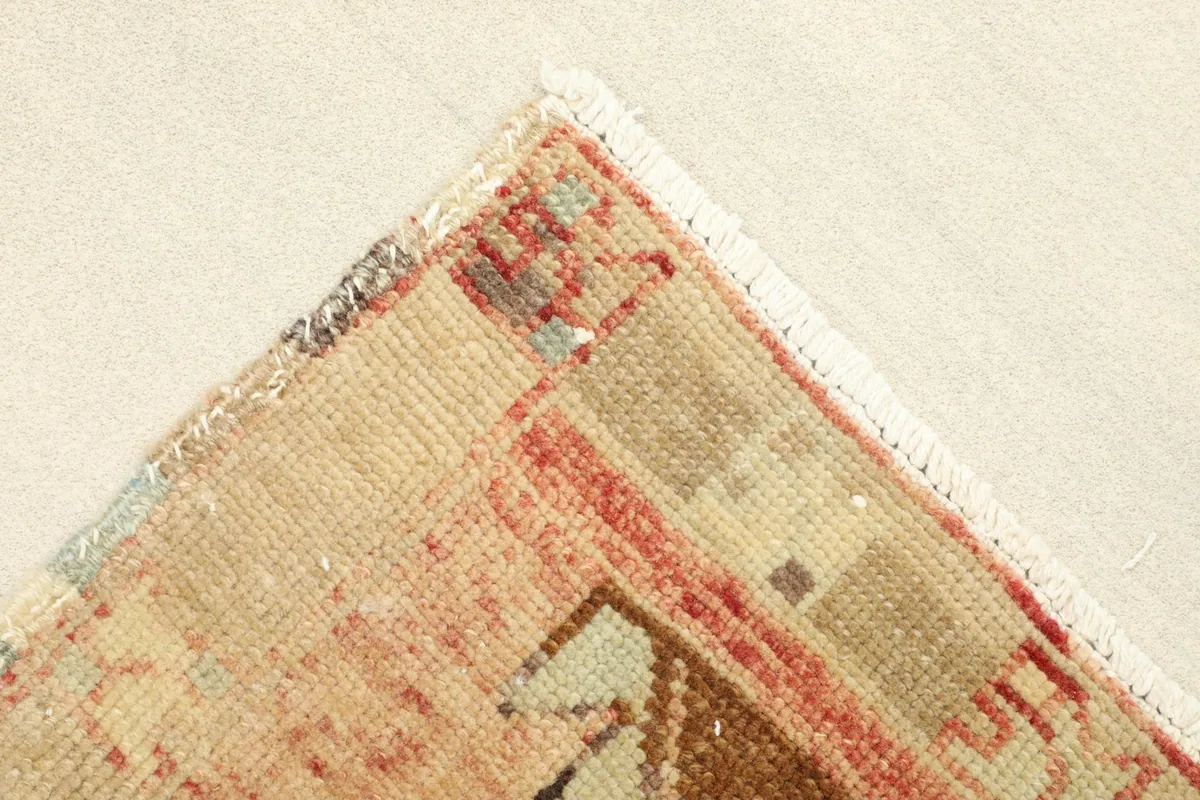 Corner view showing the reverse side of the rug, revealing the cotton foundation and knotting.