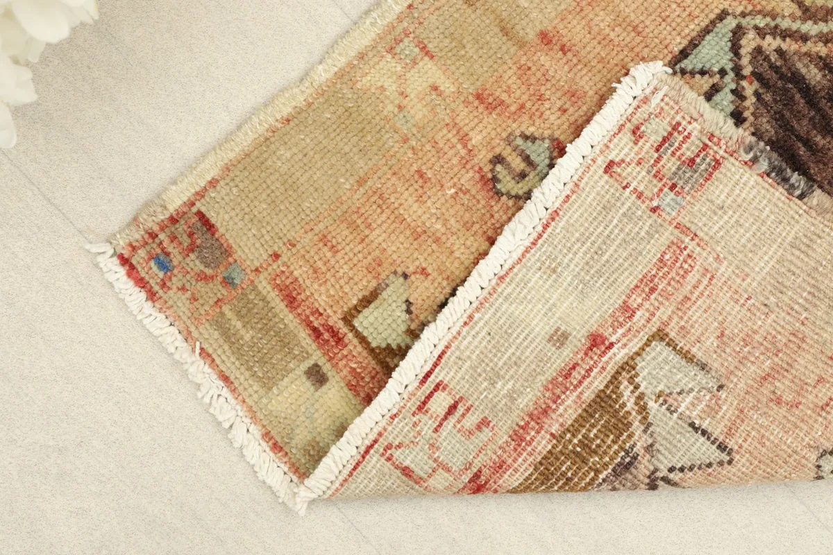 Partial view of the rug folded, highlighting the thickness and flexibility of the vintage textile.