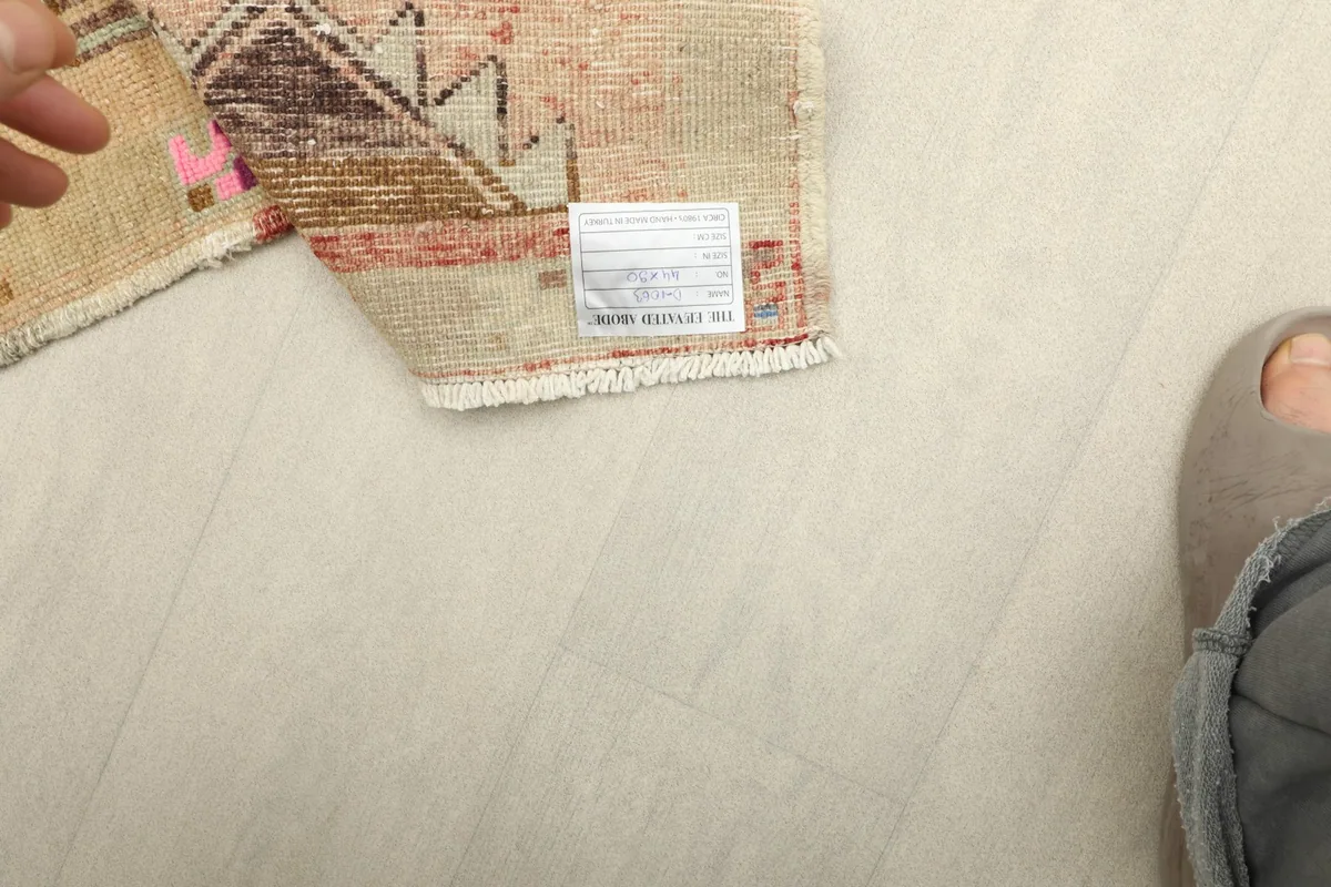 Corner of the rug with a label, offering a sense of scale next to a person's foot.