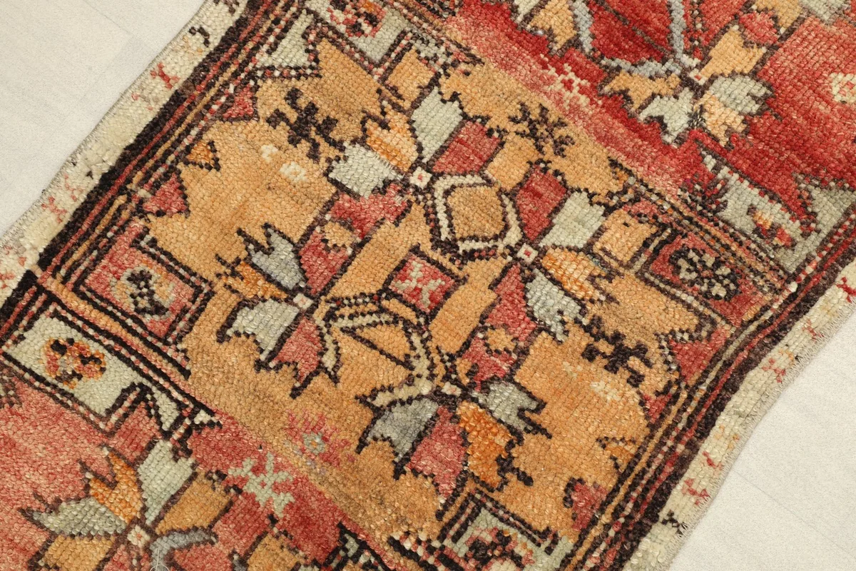 Angled view highlighting the wool pile texture and vibrant orange and red tones of the rug