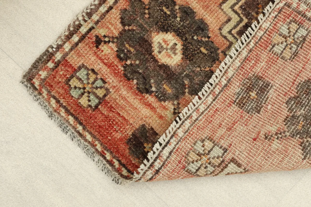 View of the rug's low wool pile and hand-knotted construction, with a folded edge