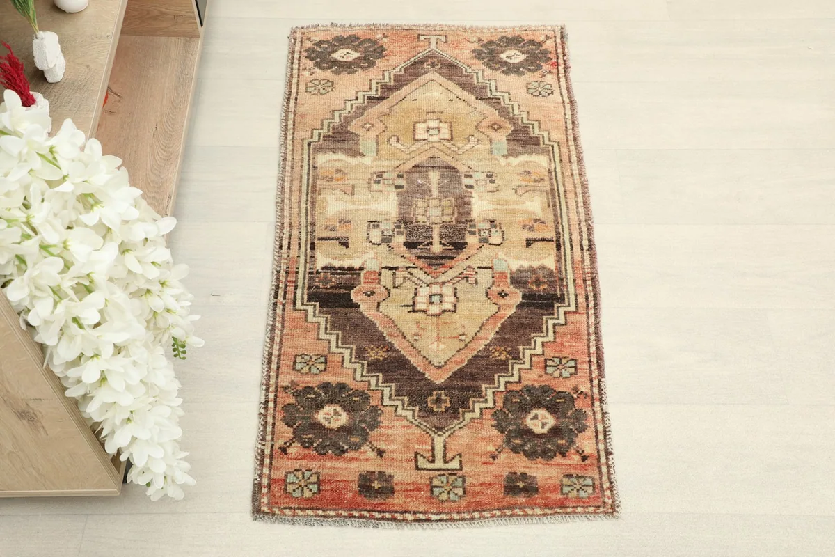 Overhead view of the small hand-knotted rug, showing its full design and warm color palette