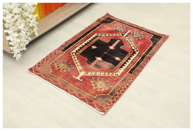 Full top view of the red and black geometric vintage Anatolian doormat on a white background