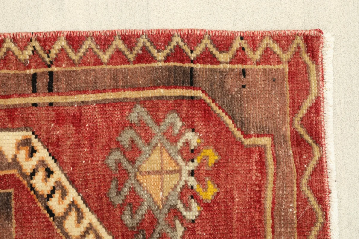 Close-up of the lower right corner, revealing the red field, brown border, and detailed tribal motifs