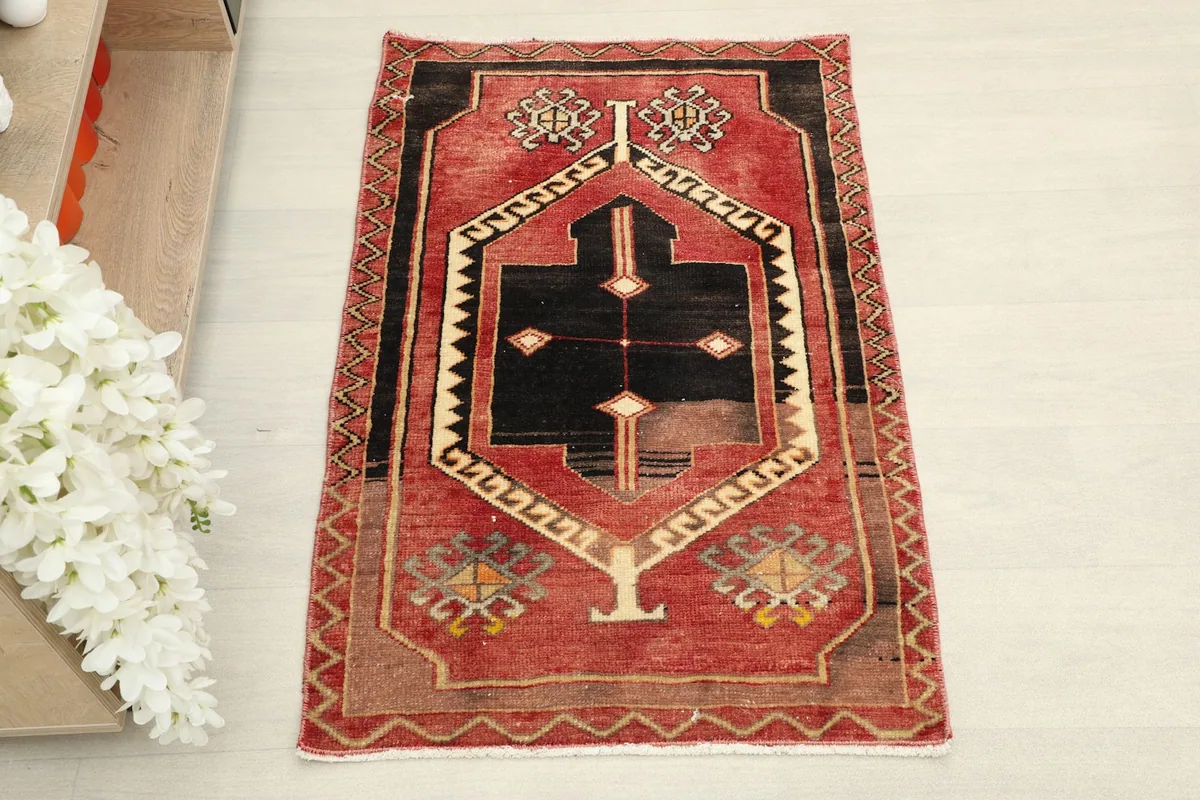 Overhead view of the vintage Anatolian rug, highlighting its central black medallion and red field