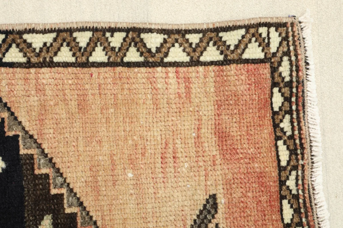 Close-up of the rug's border and the faded rose field, highlighting the vintage patina.