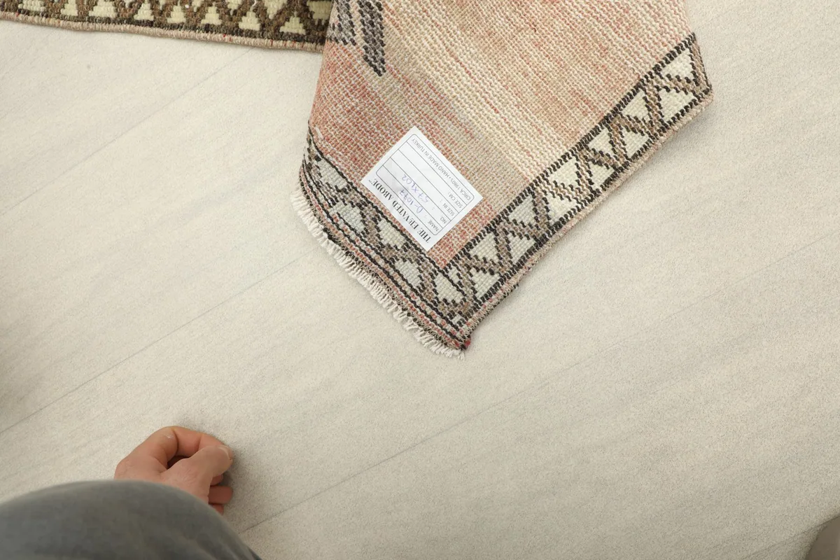 Corner of the rug turned over, revealing the cotton foundation and a product label.