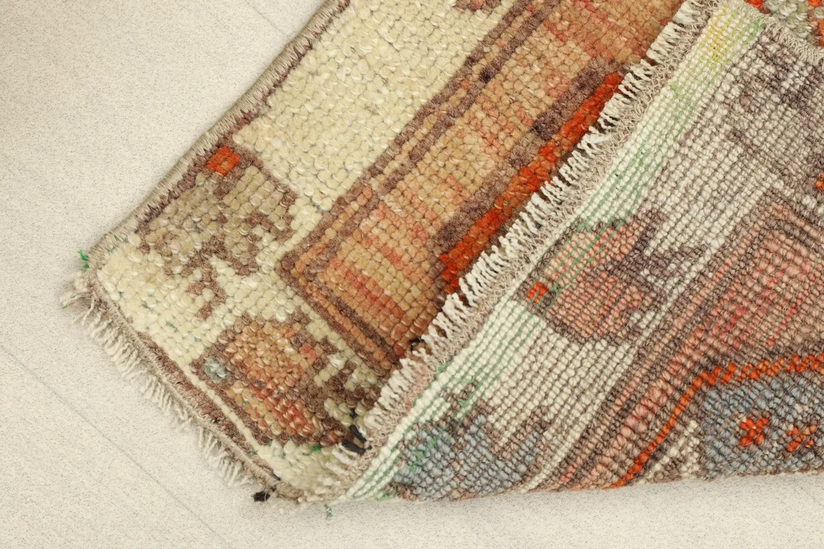 The doormat folded over, revealing the cotton foundation and the reverse side of the hand-knotted wool.