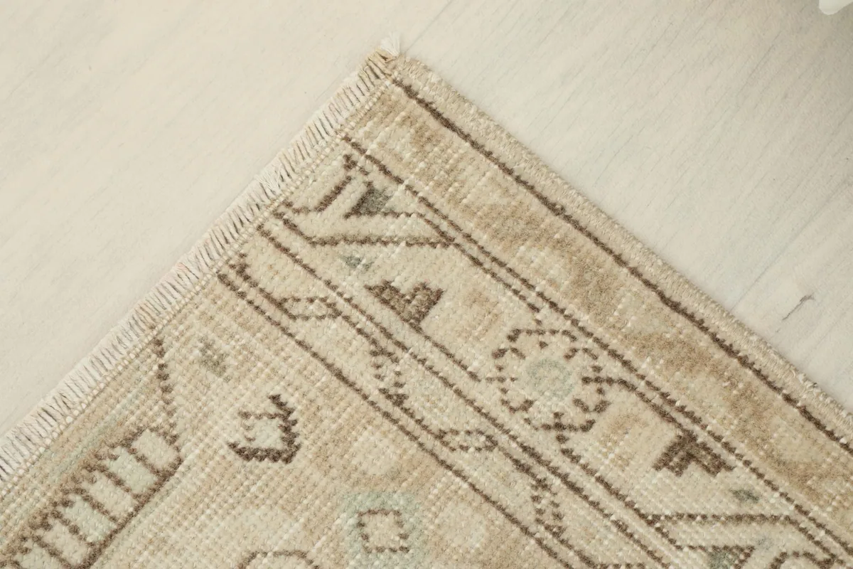 Corner view displaying the hand-knotted wool texture and slight wear on the beige rug.