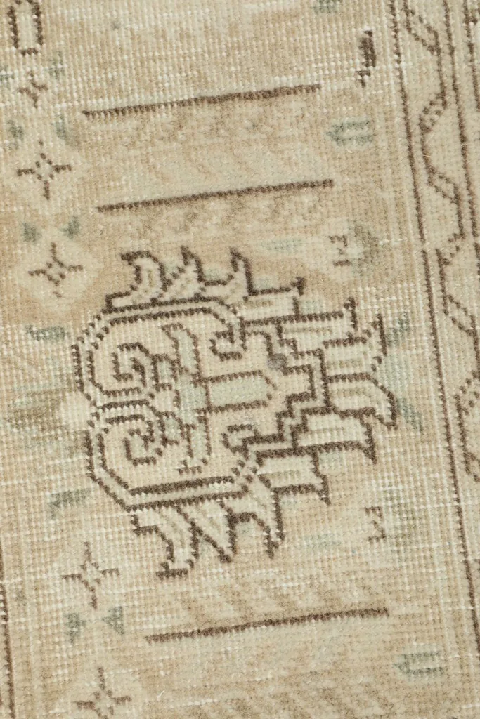 Detailed shot of the main central tribal motif with faded brown and green tones.
