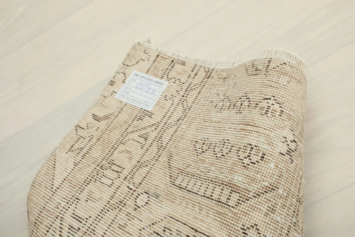 Back of the rug with a label, showing the hand-knotted structure and vintage condition.