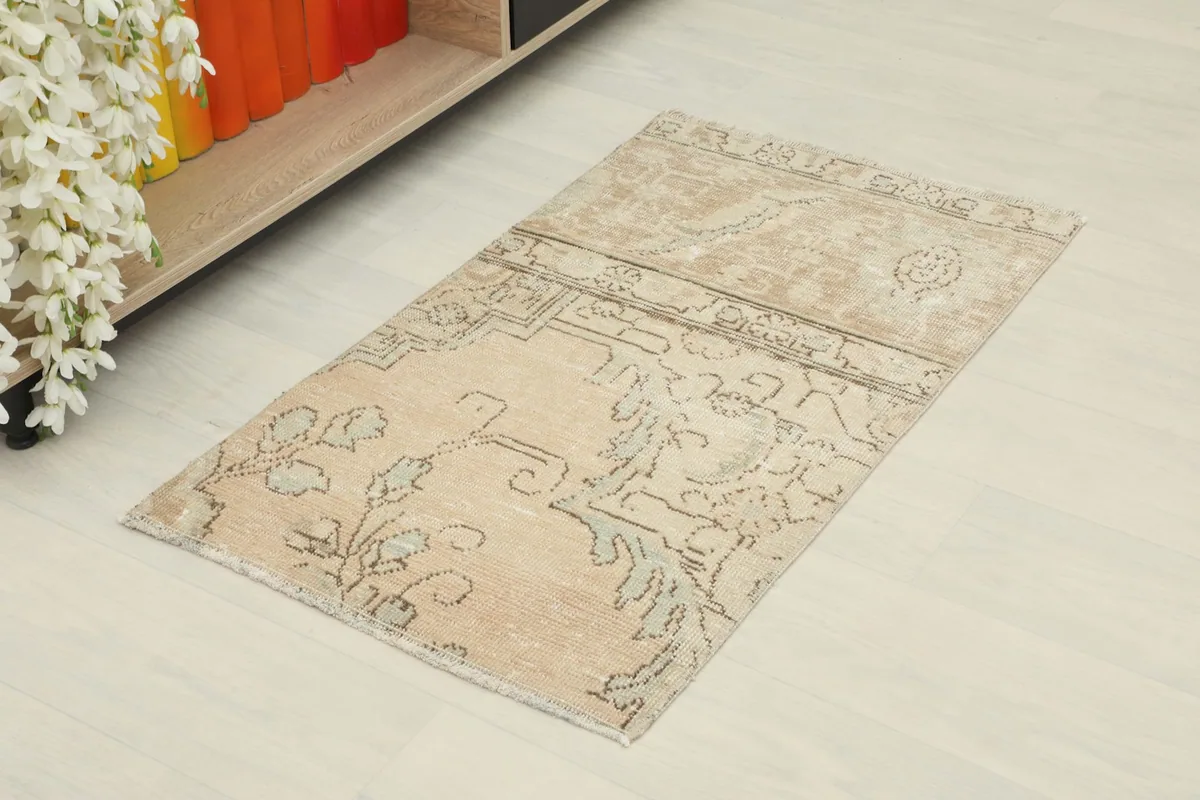 Angled view of the small tan rug showing its placement next to a low shelf