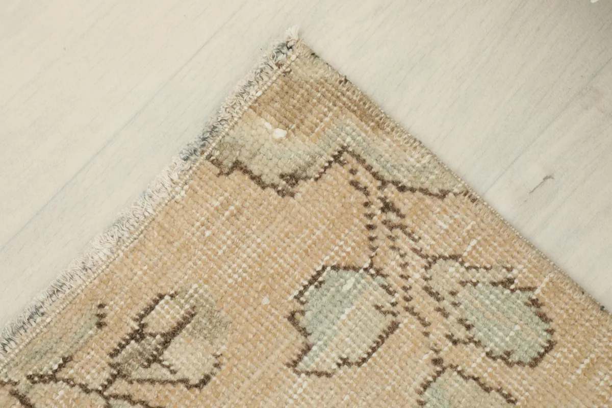 Corner view of the rug, showing the short fringe and distressed edges