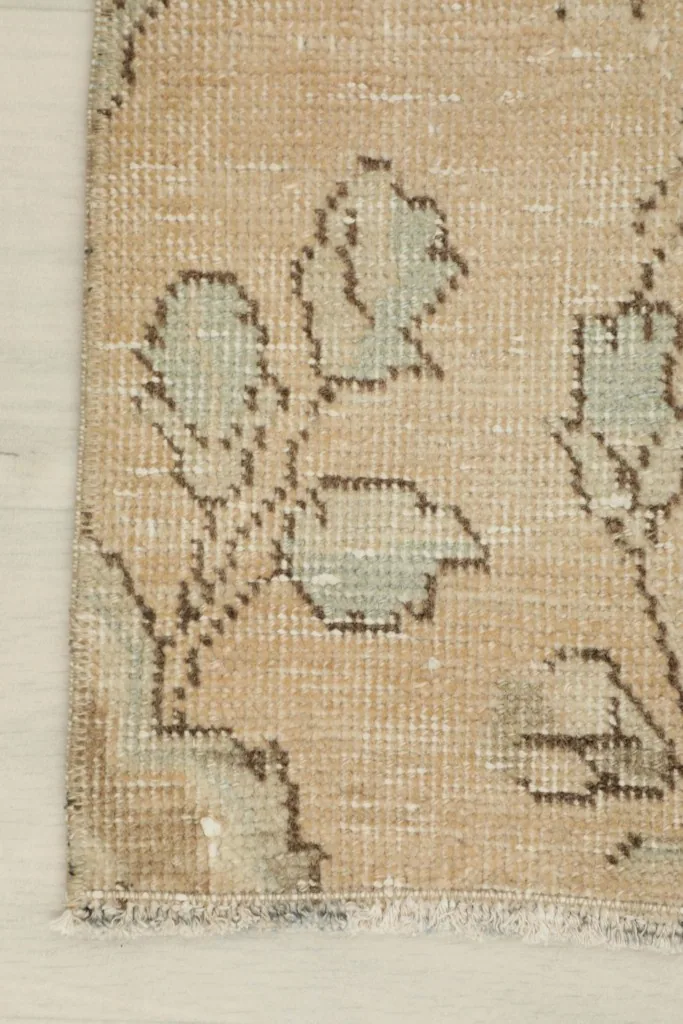 Close-up of a floral motif and the fringe along one side of the rug