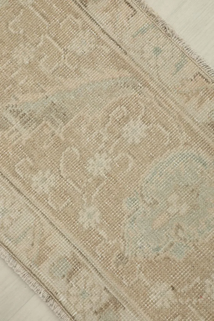 Detailed view of the tan field and faded blue geometric designs on the vintage runner