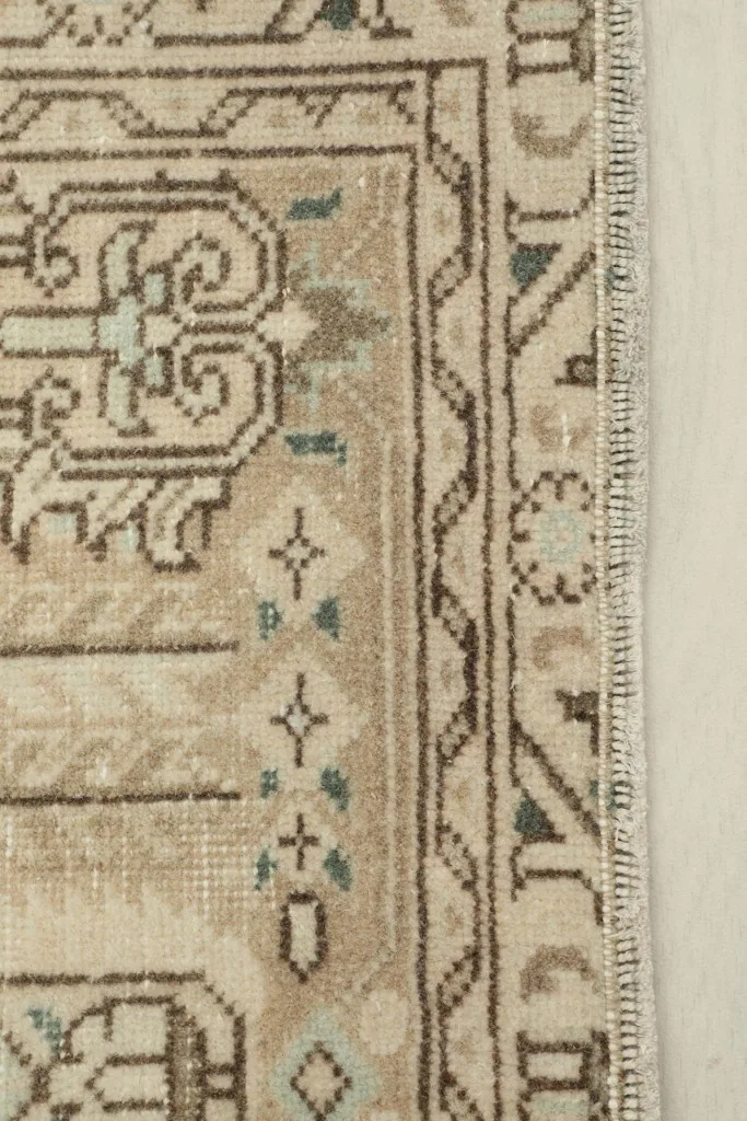 Close-up detail of the rug's border and fringe, highlighting the brown and beige tones.