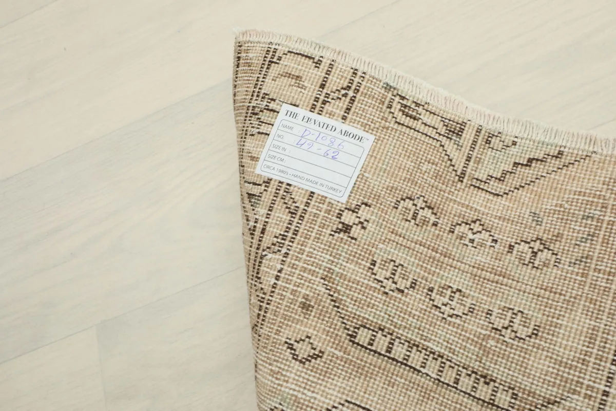 The back of the rug with an information label, showing the tight hand-knotted cotton foundation.