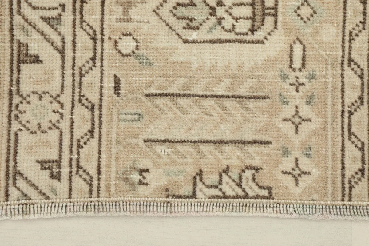 Close-up detail of the rug's border and central motifs, showing the brown and gray tones.