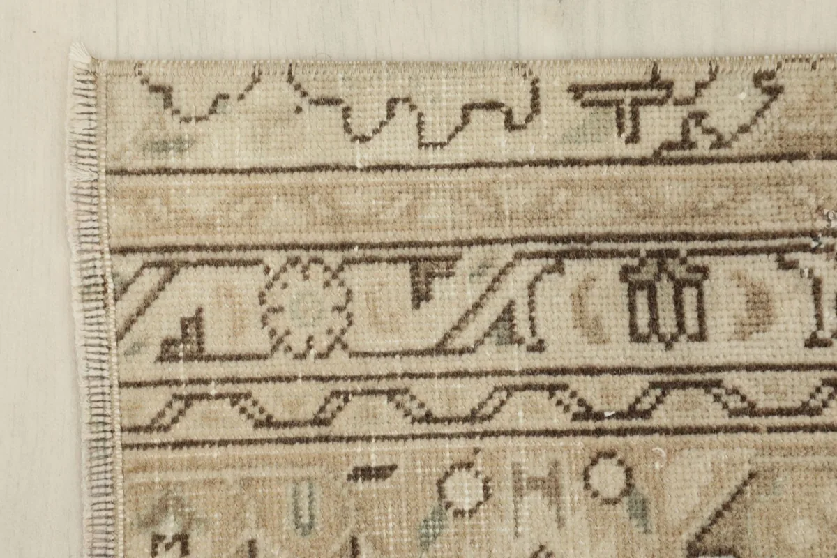 Corner detail of the rug, showing the fringe and the edge of the geometric border design.