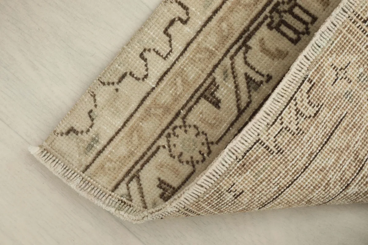 View of the rug folded to reveal the back, showing the cotton foundation and knotting.