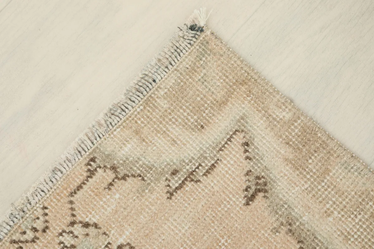 Corner view of the vintage rug, emphasizing the worn texture and muted color palette.