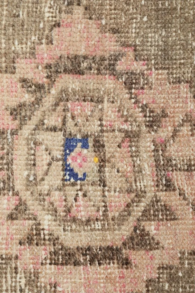 Detailed close-up of the central motif, revealing individual knots and color variations including blue