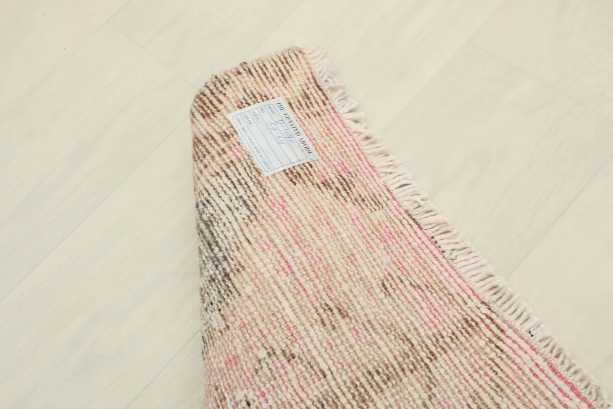 View of the back of the rug, showing the knotting structure and a small tag