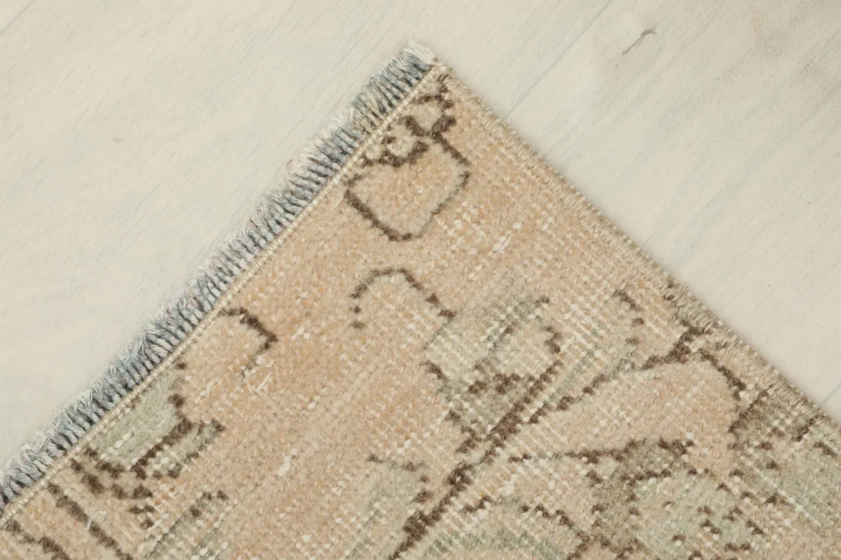 Overhead angled view of one corner of the rug, highlighting the soft fringe and wool texture.