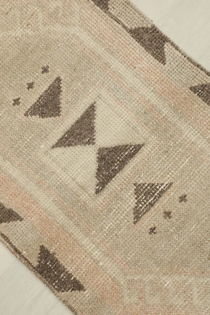 Detailed view of the central brown geometric patterns on the beige field of the rug