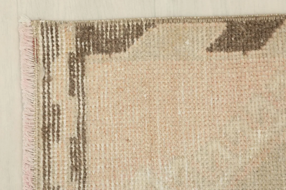 Corner detail of the rug, showing the blend of beige and brown tones and the low pile