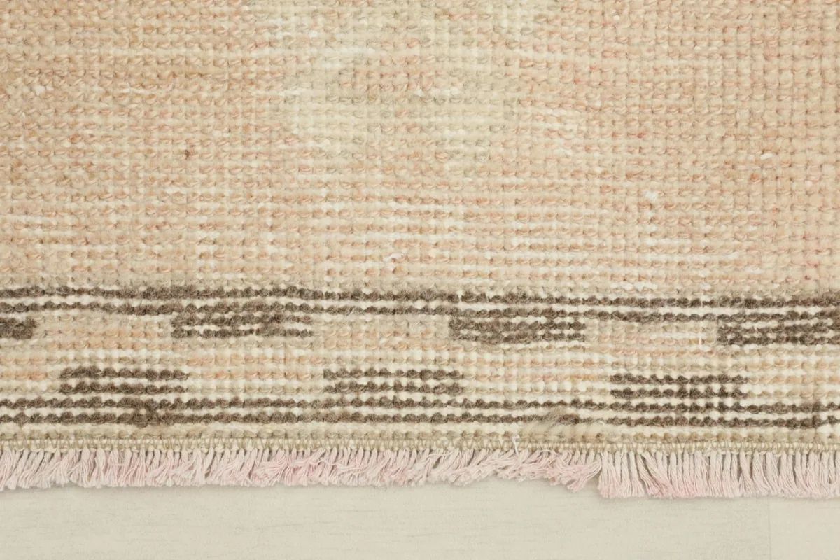 Close-up of the rug's border and fringe, showing the hand-knotted texture and slight wear