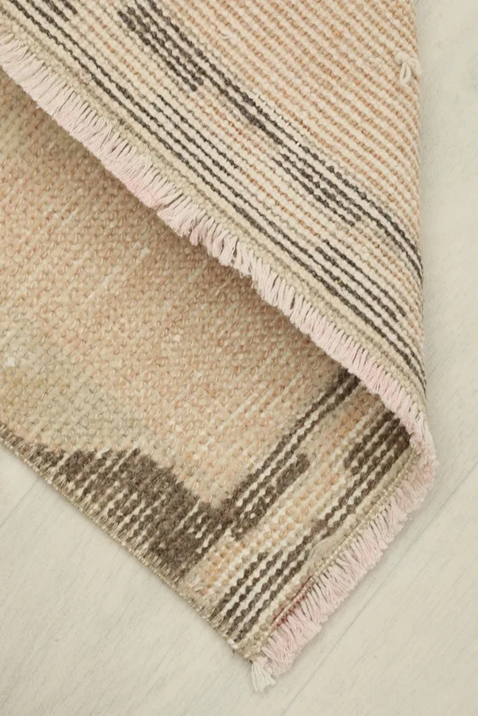 The rug folded to reveal its thickness and the cotton foundation beneath the wool pile