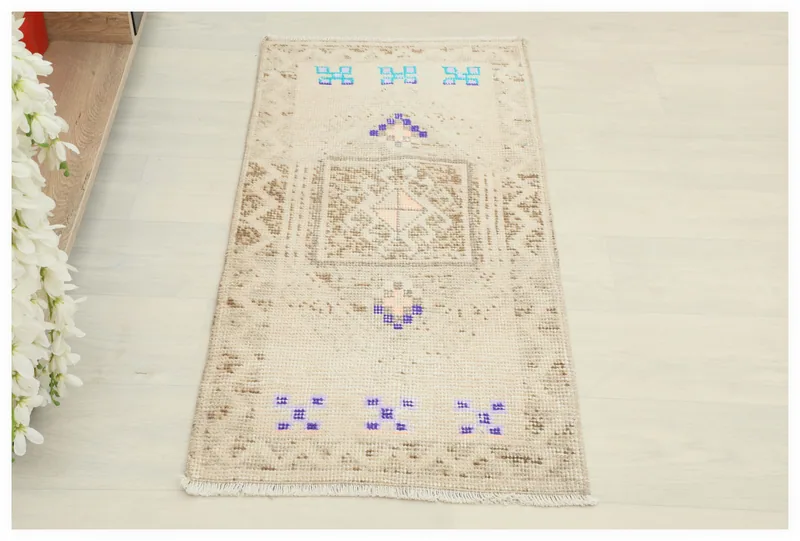 Full overhead view of the beige tribal motif rug on a white background