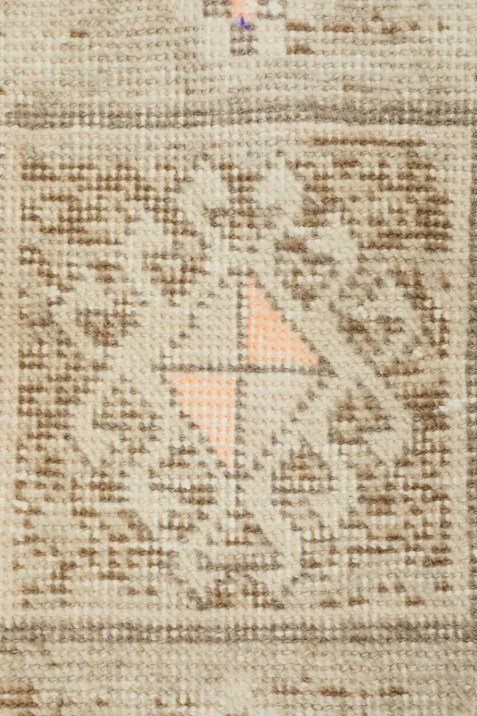Close-up of the central geometric medallion, highlighting the wool pile and subtle rose details