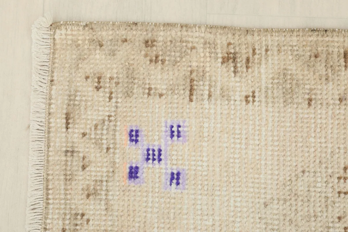 Corner detail of the rug, showing the beige background and blue tribal motifs