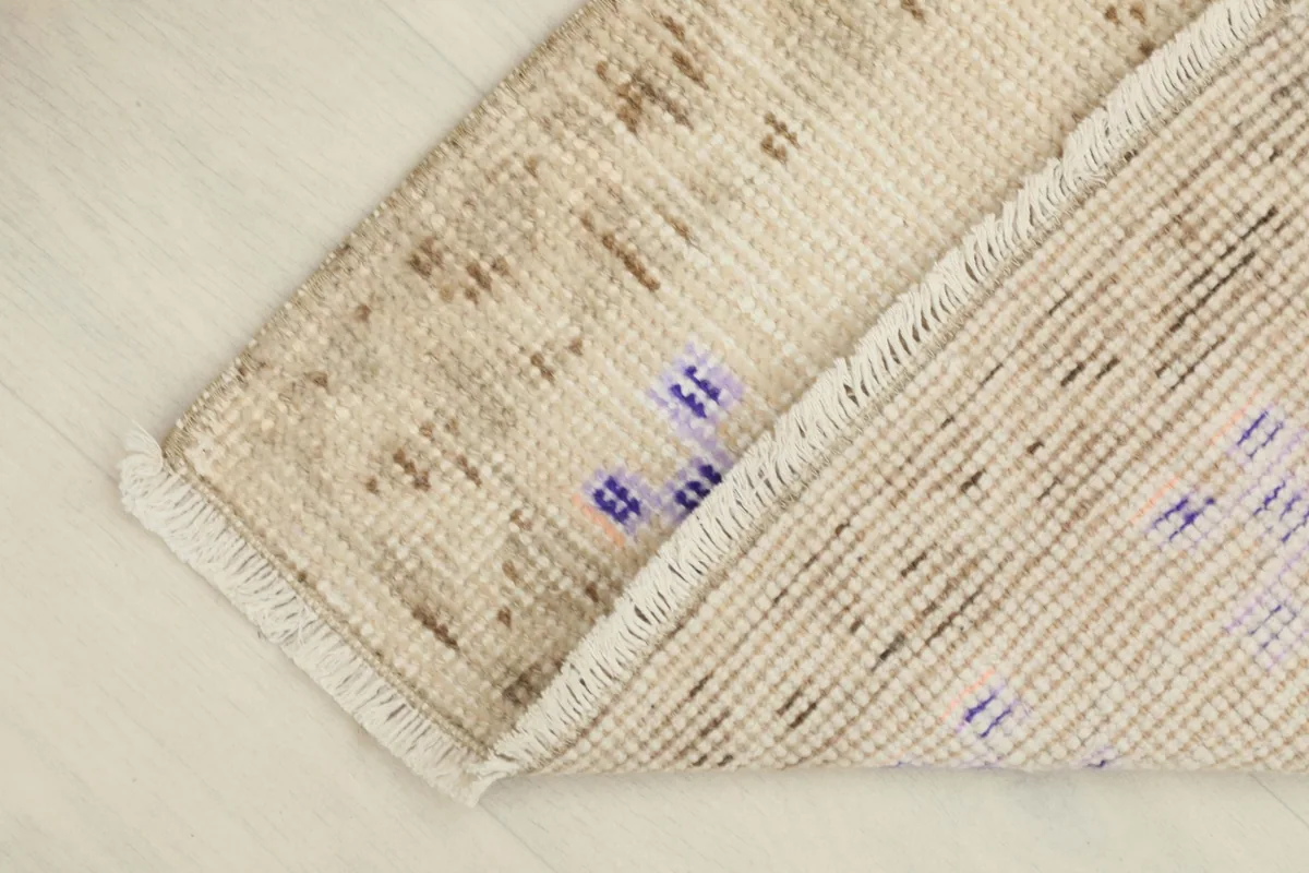 View of the rug's low pile and flexible structure, with the back partially visible