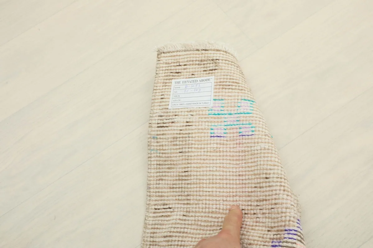 Underside of the rug showing the cotton foundation and a hand-written label