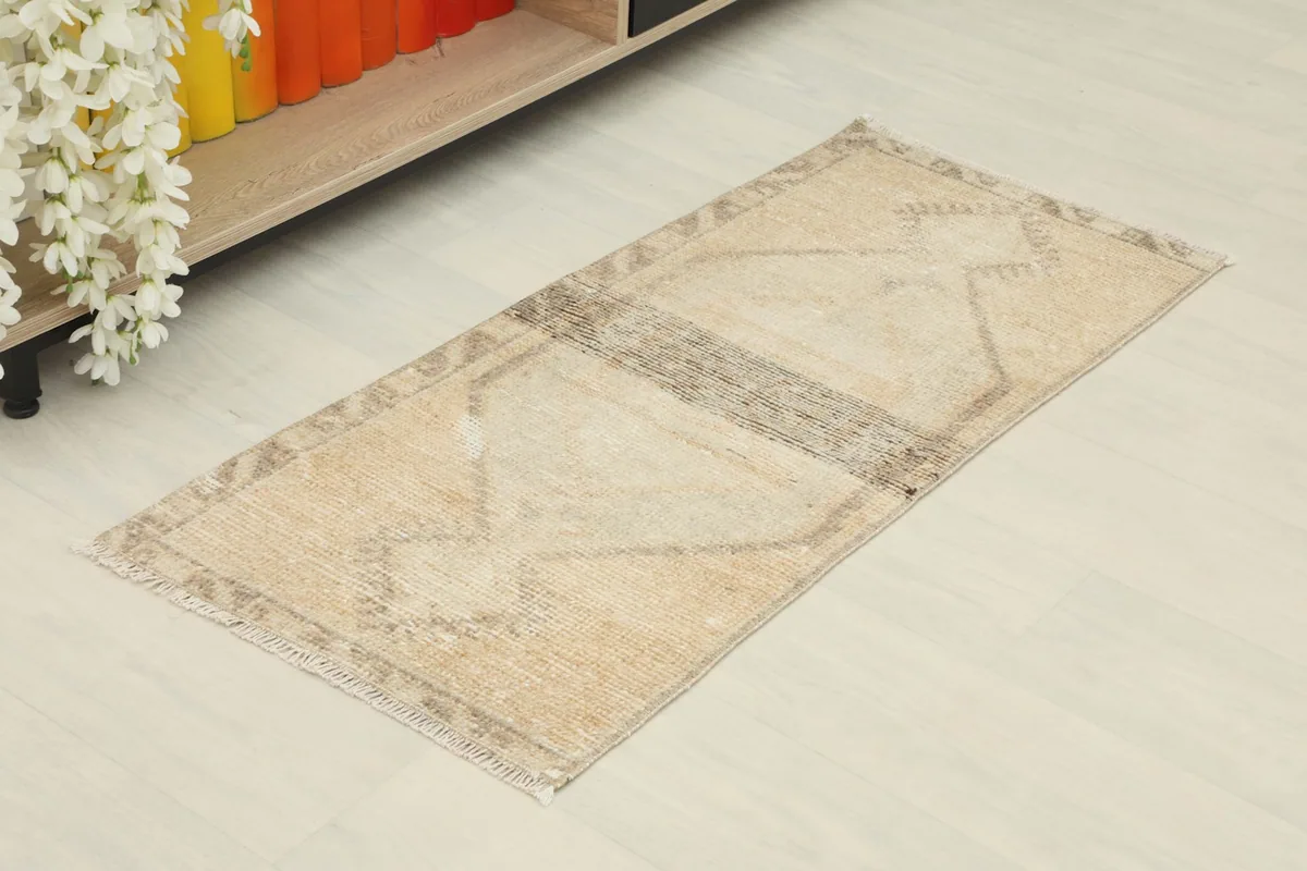 Angled view of the tan and brown geometric rug, showcasing its rectangular shape and colors.