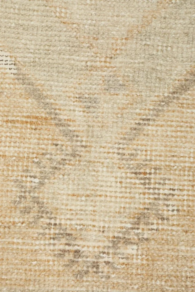 Close-up of the subtle beige and tan geometric patterns within the rug's field.